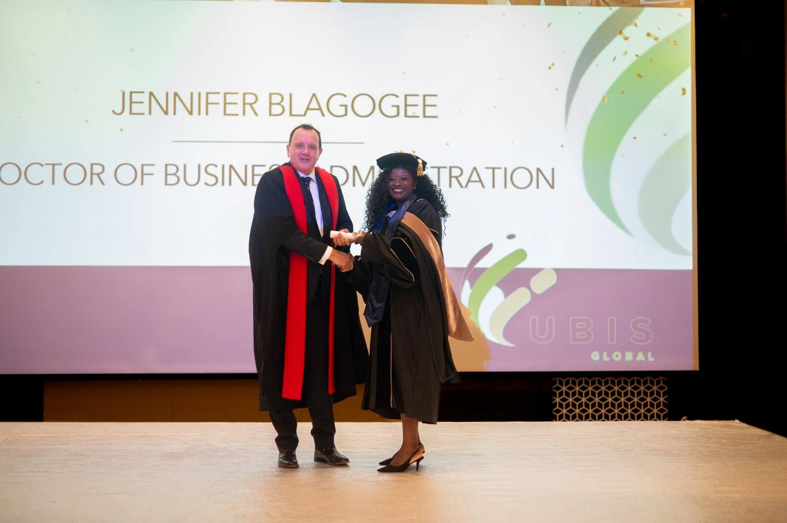 A UBIS doctoral graduate receiving their degree on stage at a graduation ceremony